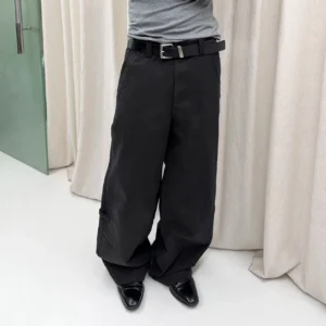 Black washed wide-leg cotton trousers shown in a cropped low-angle studio view with a relaxed streetwear fit, leather belt, and dress shoes