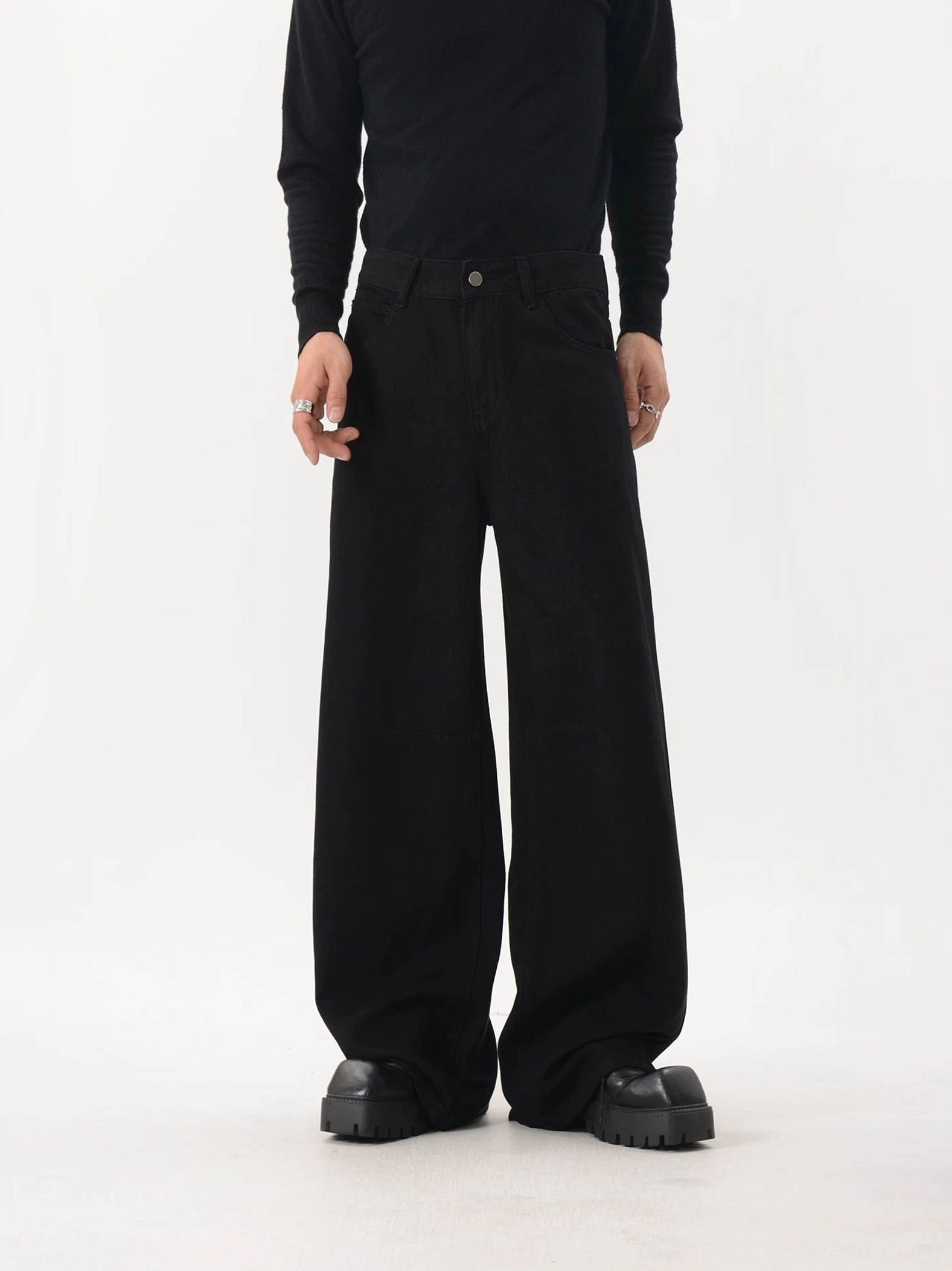 Black washed wide-leg streetwear pants displayed from the front with relaxed oversized cut, practical front pockets, structured waistband, and chunky footwear styling