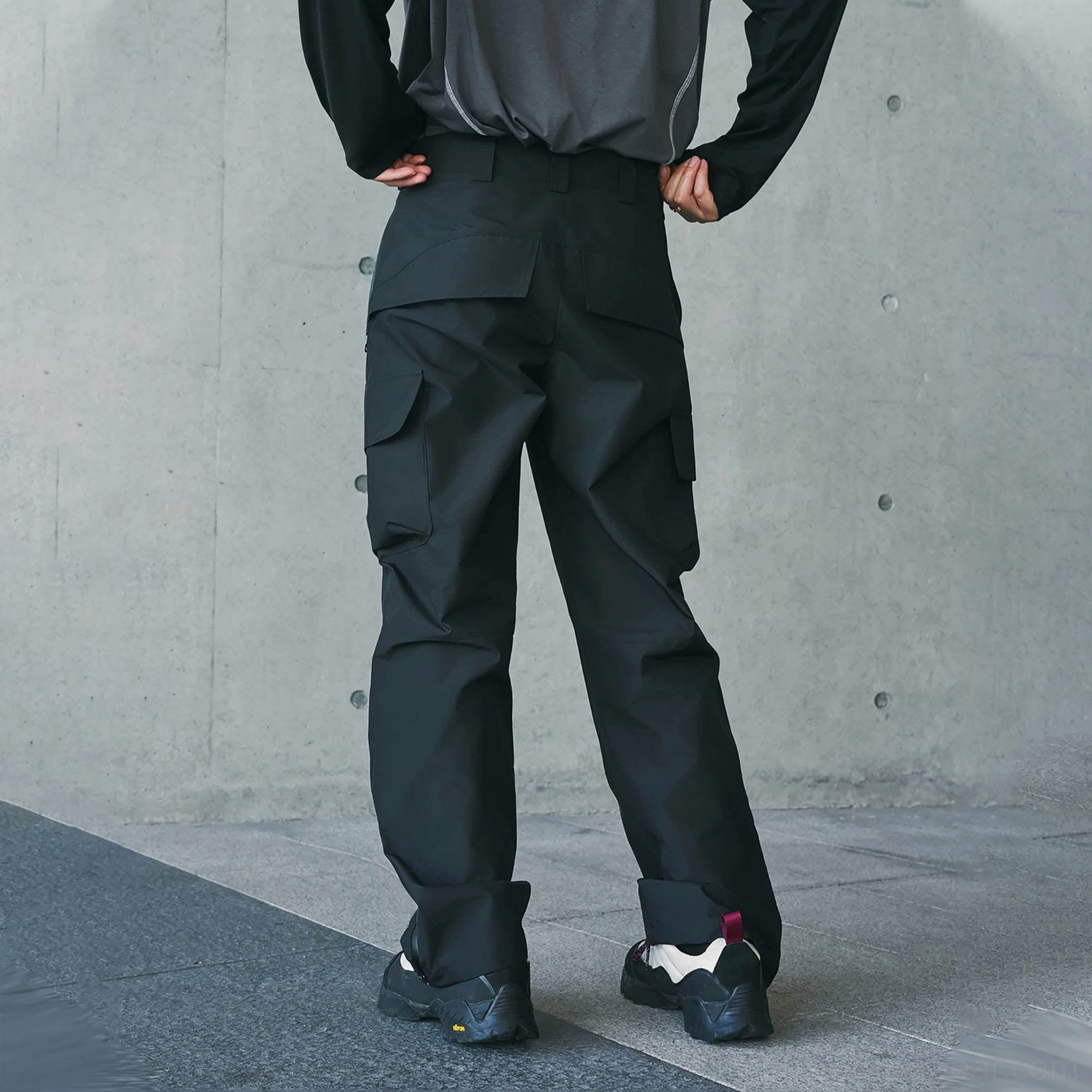 Black waterproof cargo pants shown from the rear with rear cargo pockets and a tailored straight-leg silhouette