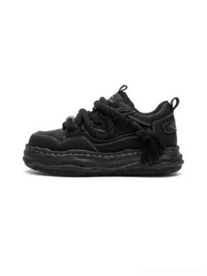 Black wavy platform sneakers in left side profile showing the sculpted 7CM platform sole, twisted rope laces, metal toggle, contrast stitching, and heel tassel detail