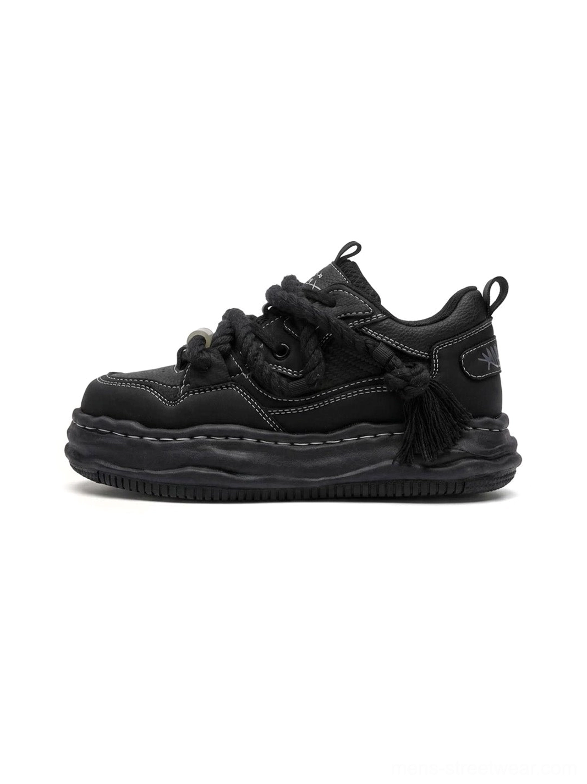 Black wavy platform sneakers in left side profile showing the sculpted 7CM platform sole, twisted rope laces, metal toggle, contrast stitching, and heel tassel detail