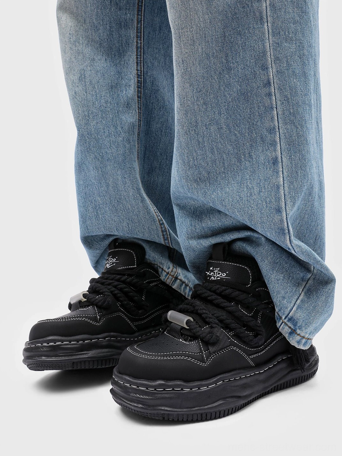 Black 7CM wavy platform sneakers styled with loose blue jeans in a casual Korean streetwear outfit, showing the chunky sole and contrast stitching