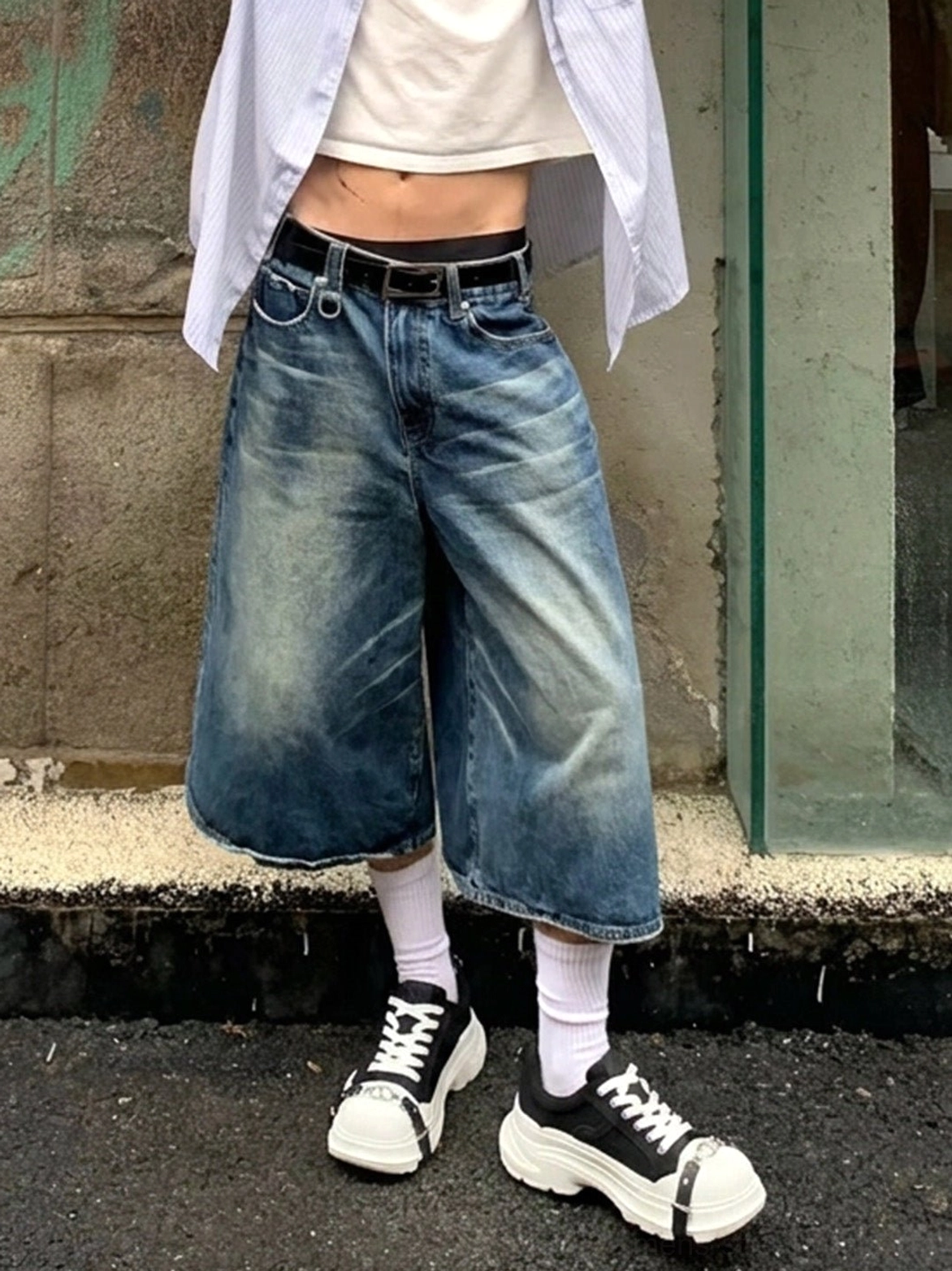 Black and white buckle platform canvas sneakers styled with cropped denim shorts and white socks in an urban street setting