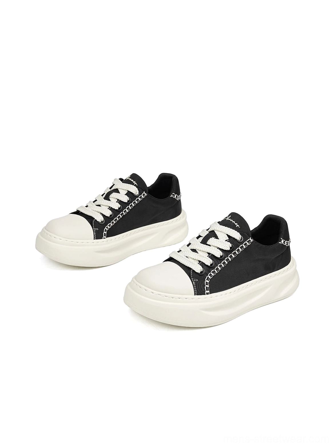 Black and white chain-trim canvas platform sneakers arranged in a front flat-lay view with chunky streetwear soles