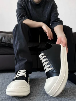 Black and white chunky low-top sneakers worn with all-black casual streetwear in an overhead indoor lifestyle view