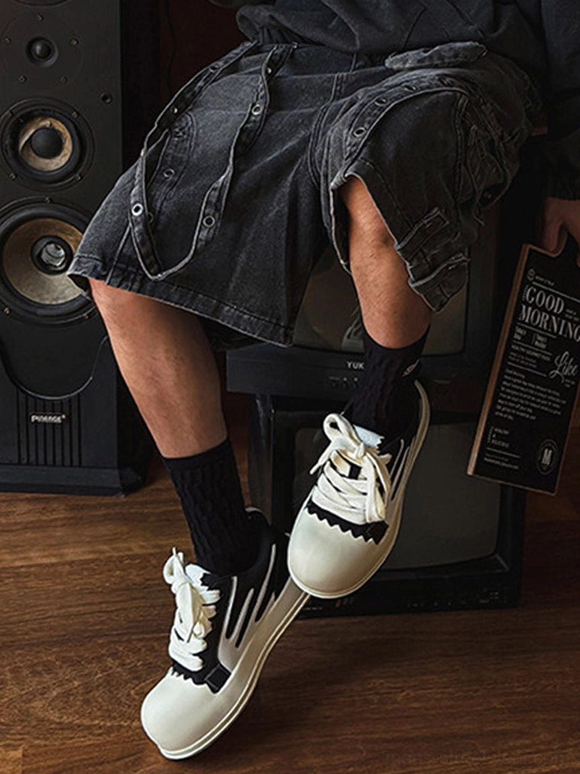 Black white stripe chunky platform sneakers with oversized toe caps worn with black socks and denim shorts indoors