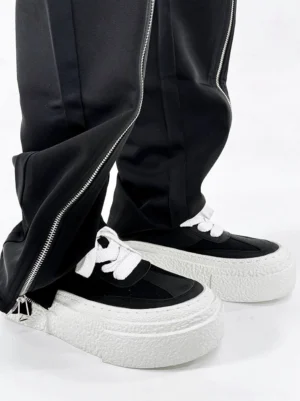Black and white chunky platform sneakers styled with black flared zippered trousers in a Korean streetwear outfit