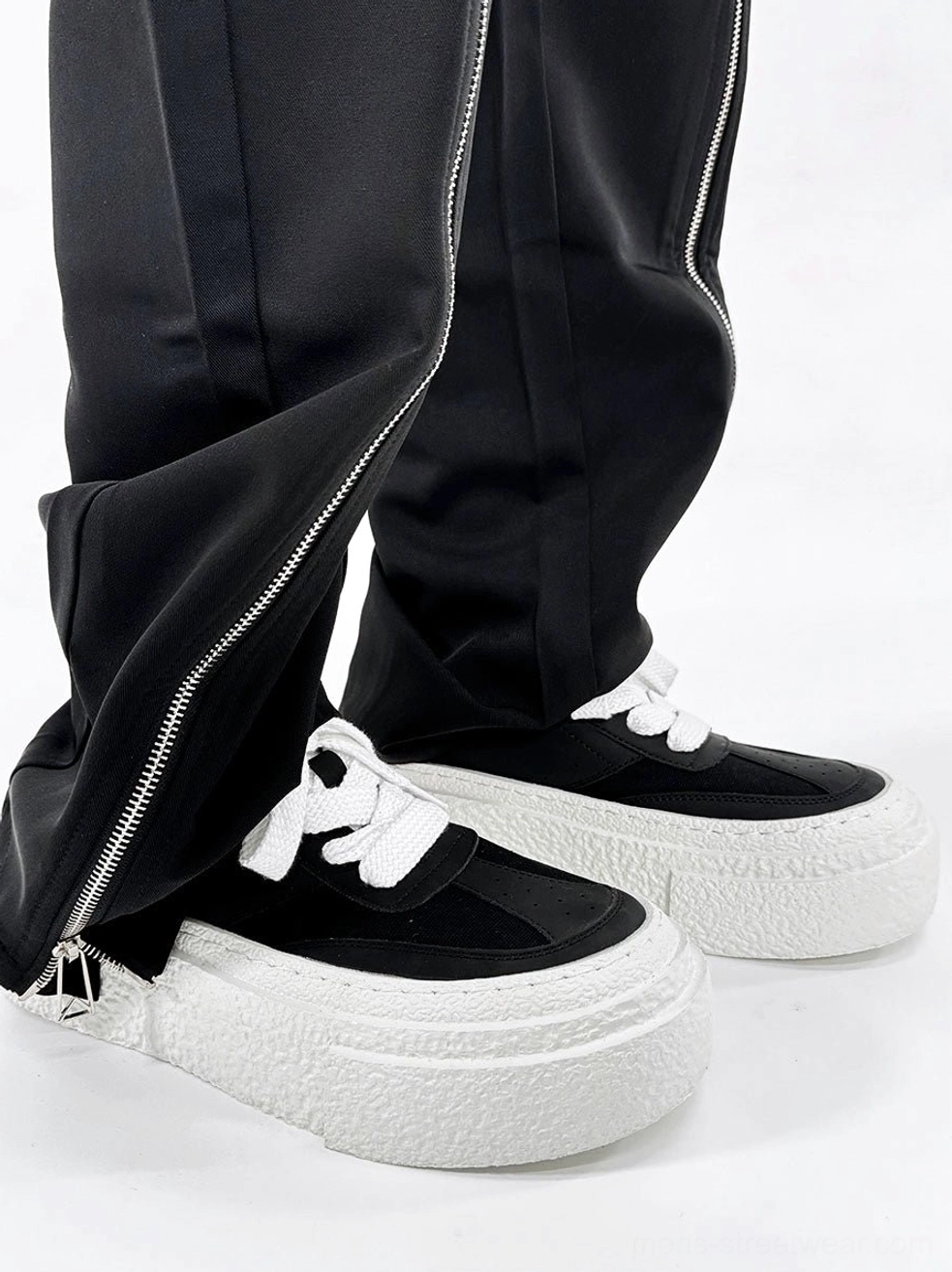 Black and white chunky platform sneakers styled with black flared zippered trousers in a Korean streetwear outfit
