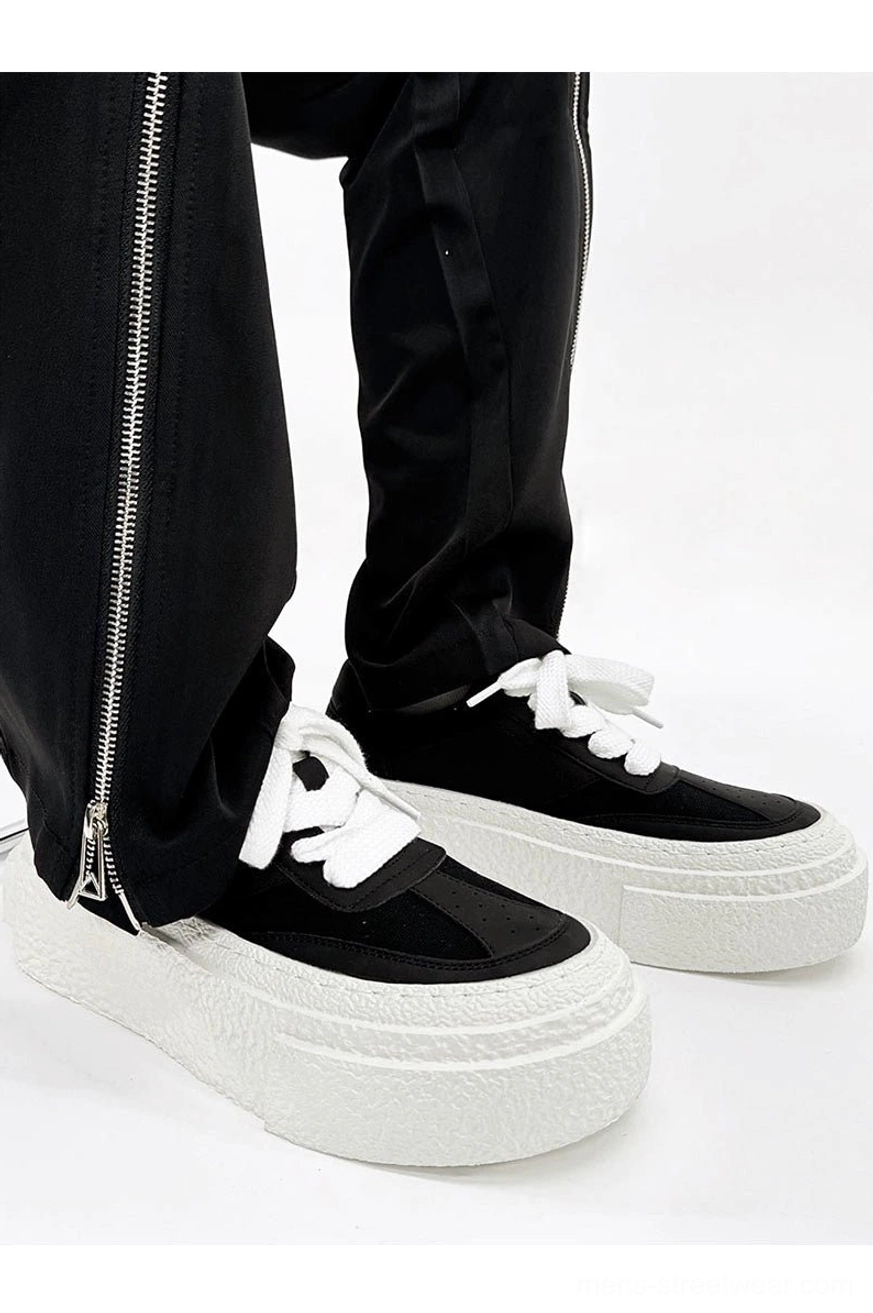 Black and white chunky platform sneakers paired with black suit trousers and metallic zipper details