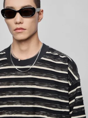 Black off-white dark grey distressed horizontal stripe crew neck long sleeve top close-up chest view textured knit fabric detail male model