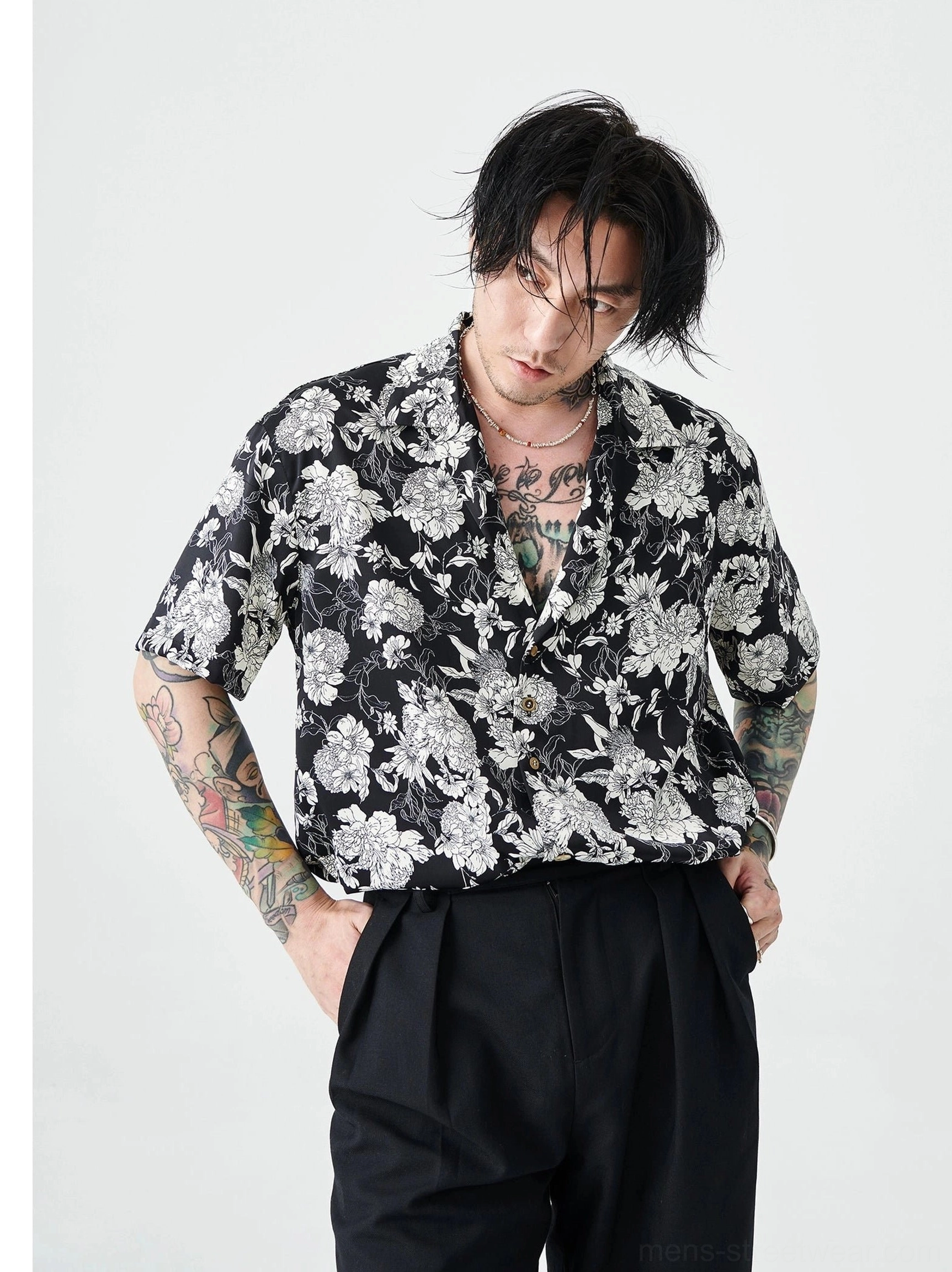 Black and white floral Hawaiian streetwear shirt worn with black high waisted trousers in a three quarter front view