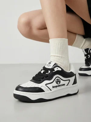 Black and white logo skate sneakers worn with beige socks showing black laces perforated toe box and cushioned low platform