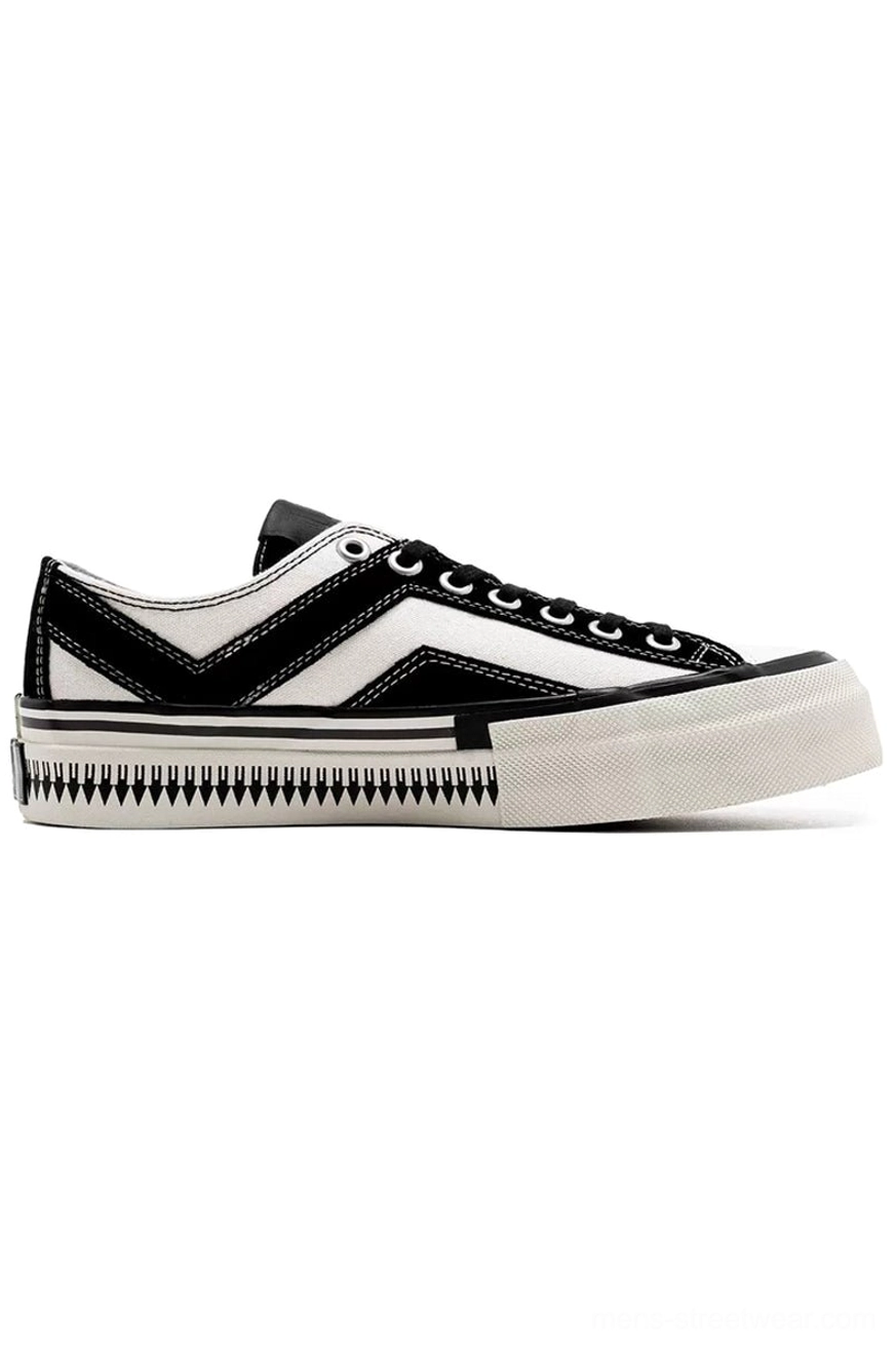 Left side view of black and white low-top canvas platform sneaker featuring black chevron stripes and serrated sole trim