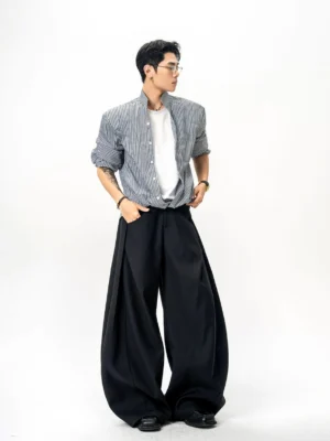 Black and white pinstripe stand collar oversized shirt shown in side view with rolled cuffs and black wide-leg trousers