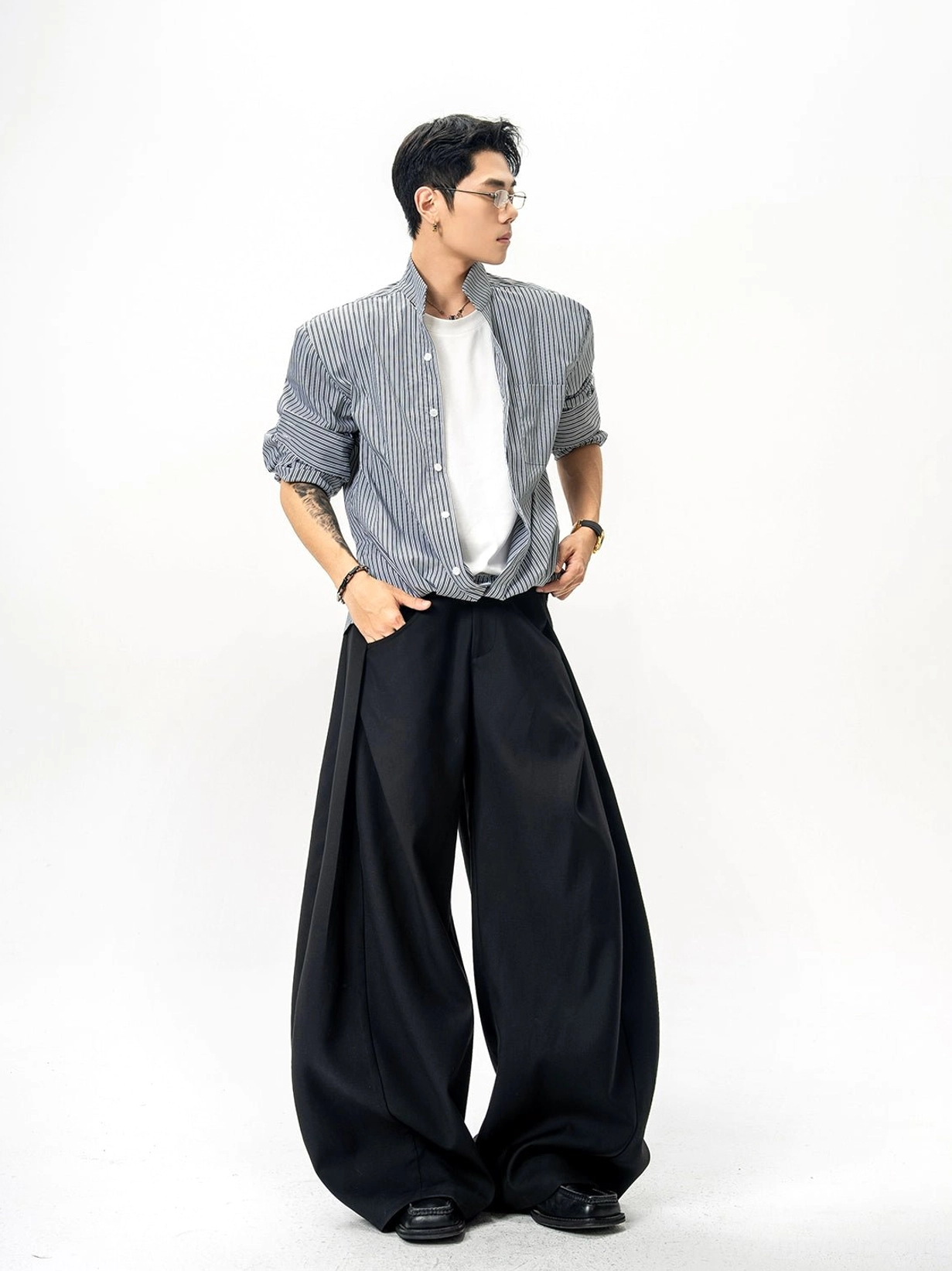 Black and white pinstripe stand collar oversized shirt shown in side view with rolled cuffs and black wide-leg trousers