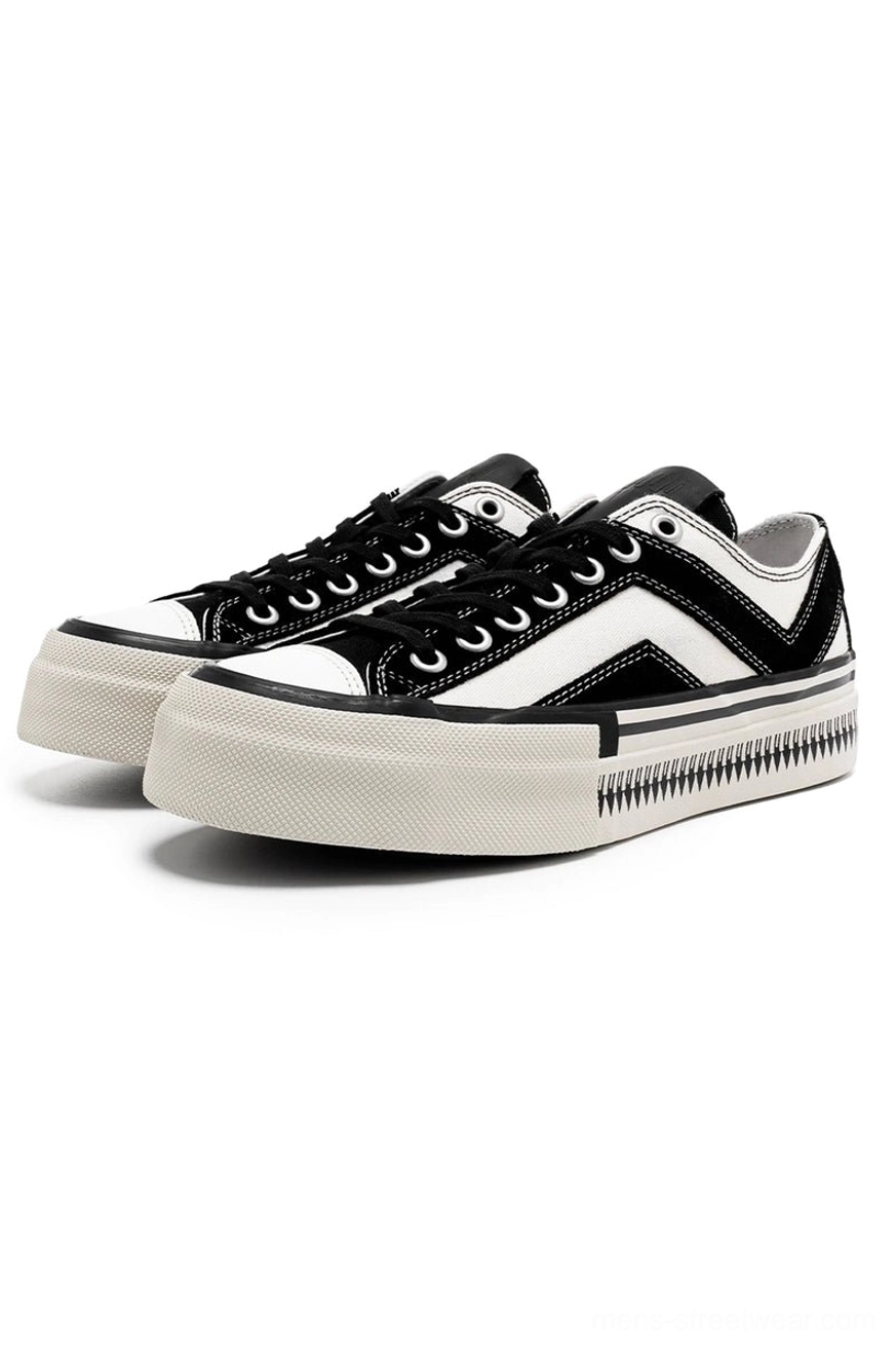 Black and white platform canvas sneakers with chevron side stripes shown in three-quarter front view on a white studio background