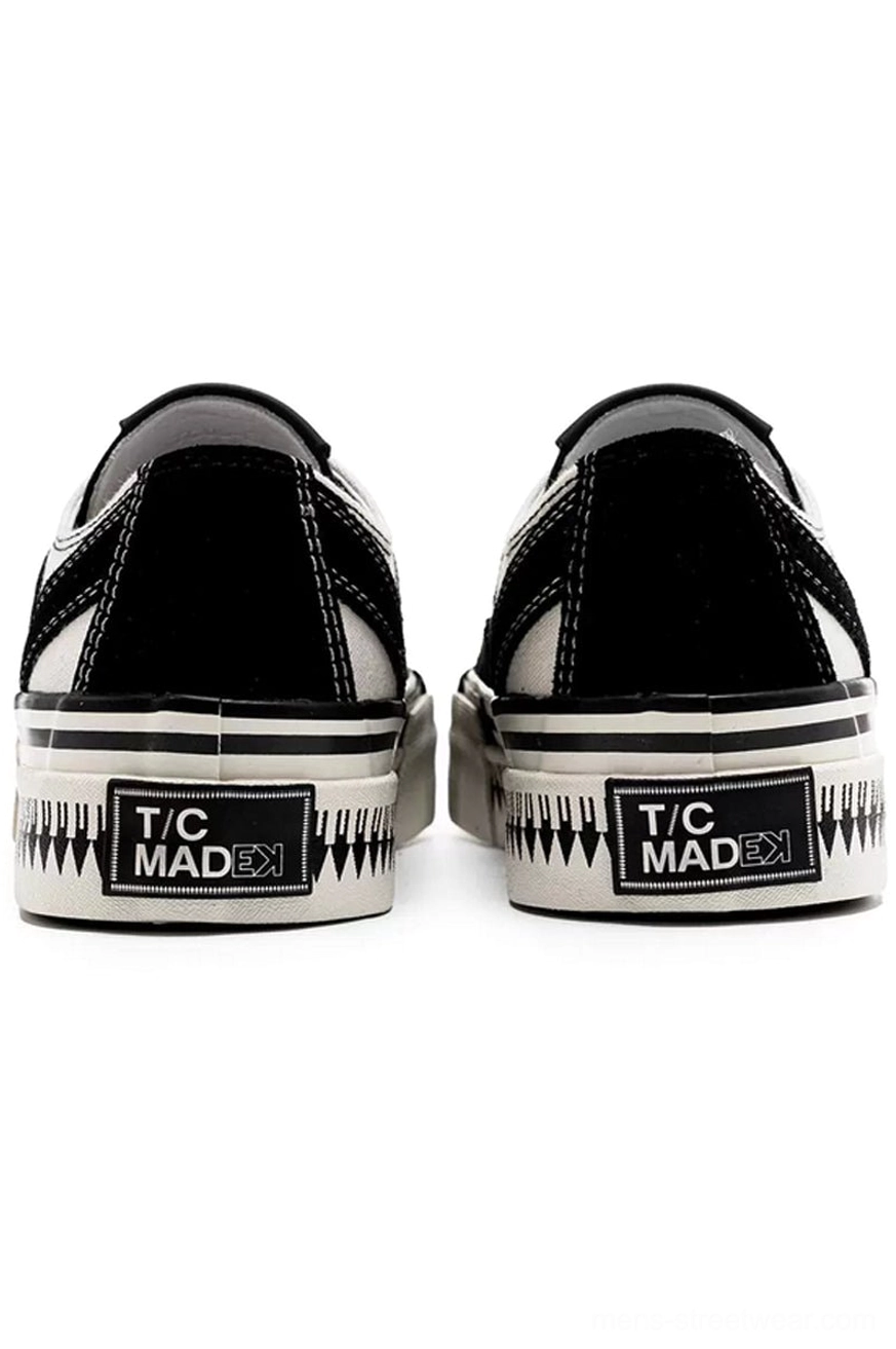 Rear heel view of black and white platform canvas sneakers with black heel panels and layered serrated rubber midsoles