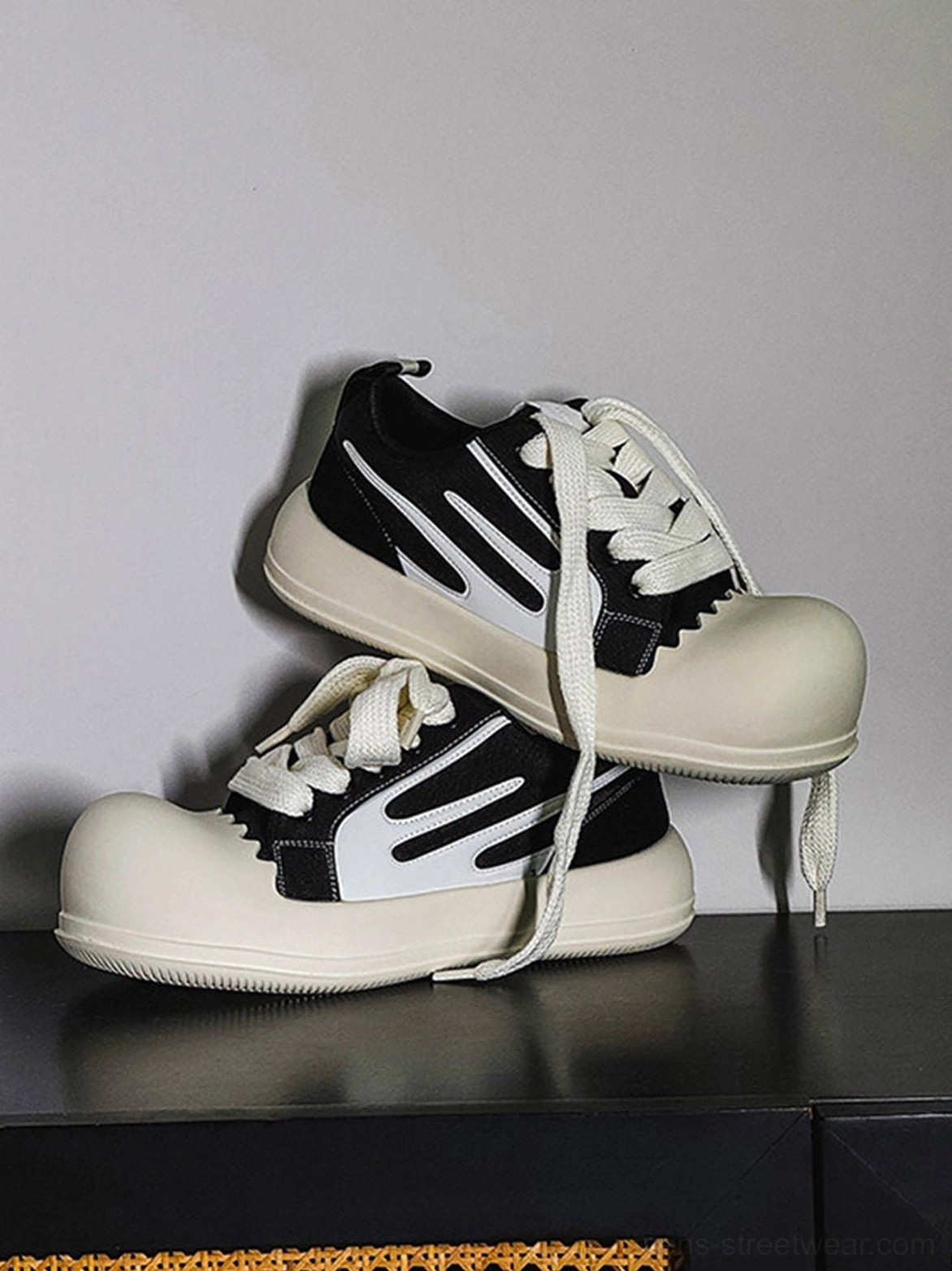 Black and white chunky platform streetwear sneakers with contrast side stripes oversized rubber toe cap and loose laces