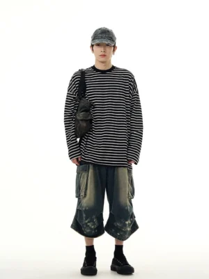 Full body styling of a black and white striped long sleeve streetwear tee with washed cargo denim shorts cap and crossbody bag