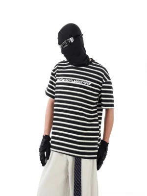 Three-quarter front view of a black and white striped streetwear T-shirt with chest graphic, relaxed drop-shoulder fit, balaclava styling, and futuristic urban fashion details