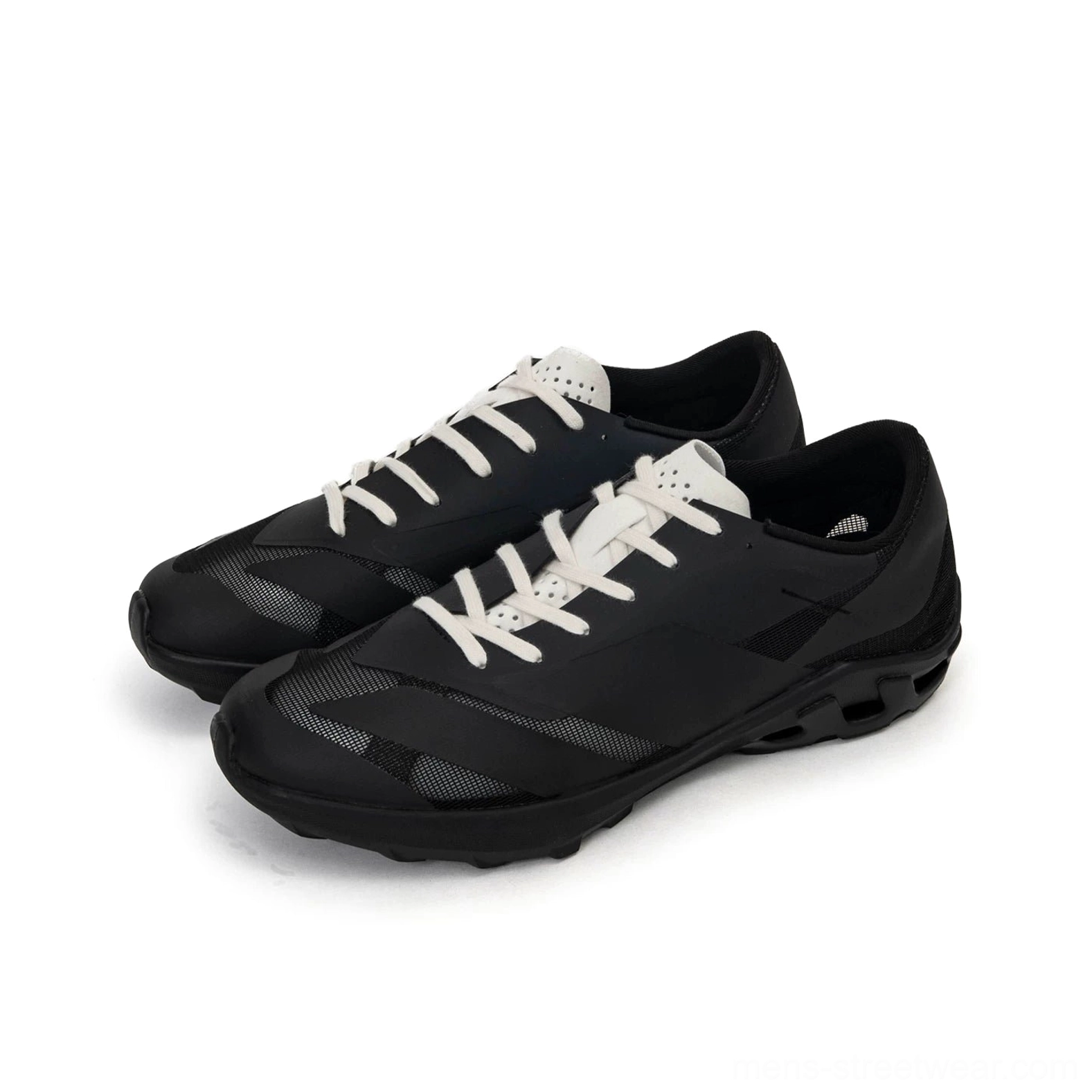 Black and white trail sneakers displayed from a front oblique angle with contrast white laces, textured matte upper, and functional chunky EVA outsole