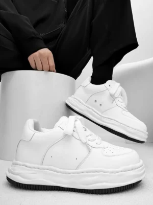 White wavy sole platform streetwear sneakers worn with all black outfit in a studio three quarter view