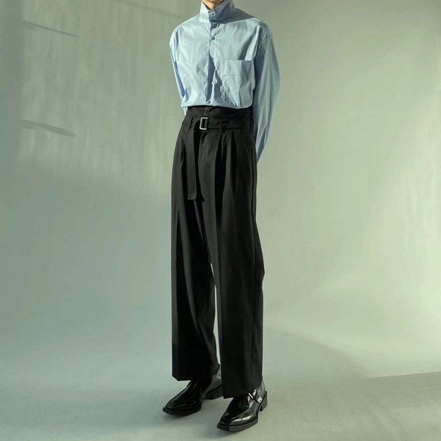 Black wide-leg belted trousers styled with a tucked-in light blue shirt, high-rise waist, and tailored silhouette in a modern streetwear outfit