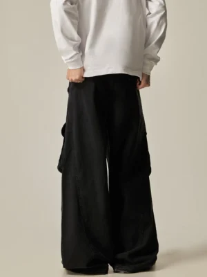 Black wide leg cargo combat pants front lower-body view with pleated details, oversized silhouette, white long-sleeve shirt, and beige casual shoes