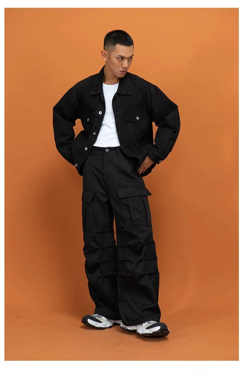Black wide-leg cargo pants shown from the full front view with layered flap pockets and contemporary urban streetwear styling