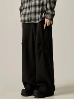 Black wide-leg cargo trousers with relaxed draped fit, side pleated utility pockets, plaid shirt styling, and chunky black boots