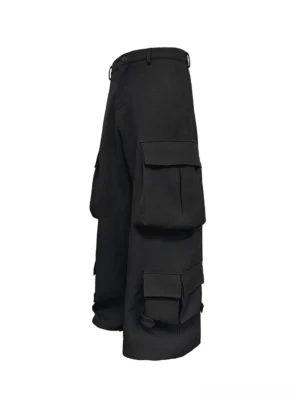 Side three-quarter view of black wide-leg cargo trousers showing stacked thigh and lower-leg flap pockets