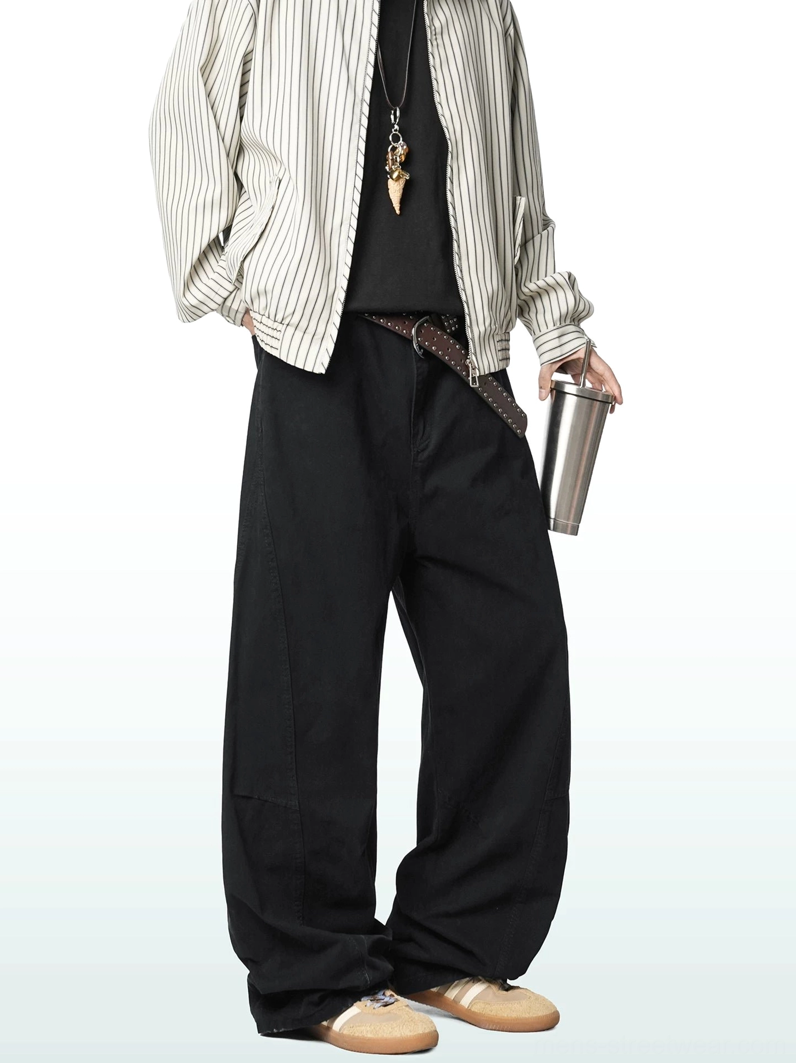 Black wide-leg cotton cargo trousers worn with a striped shirt and leather belt, showcasing the matte finish and relaxed contemporary streetwear fit