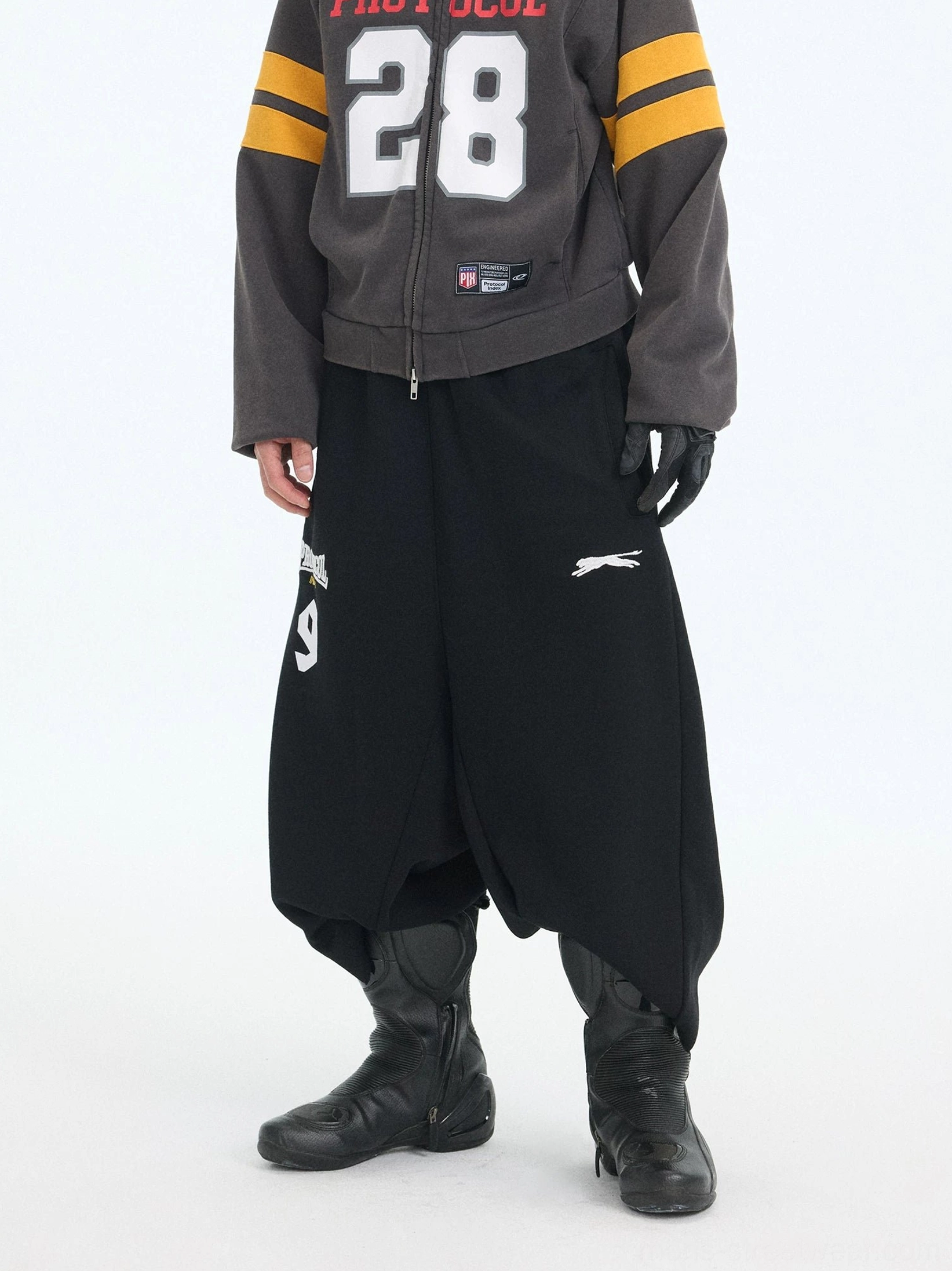 Black wide-leg cropped sweat shorts with dropped crotch, elasticated waist, and bold varsity-inspired PROTOCOL 9 thigh graphic