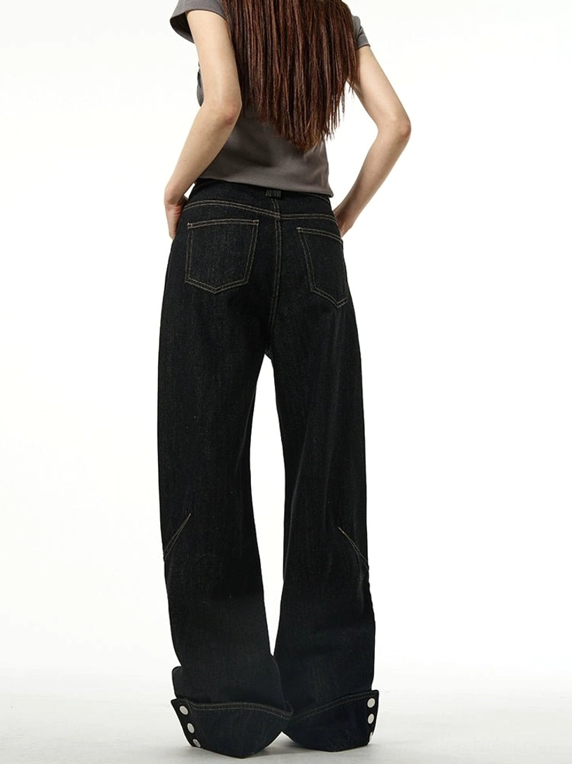Rear view of black wide-leg rolled-cuff jeans showing back patch pockets, contrast stitching, relaxed denim fit, and metal button cuff accents
