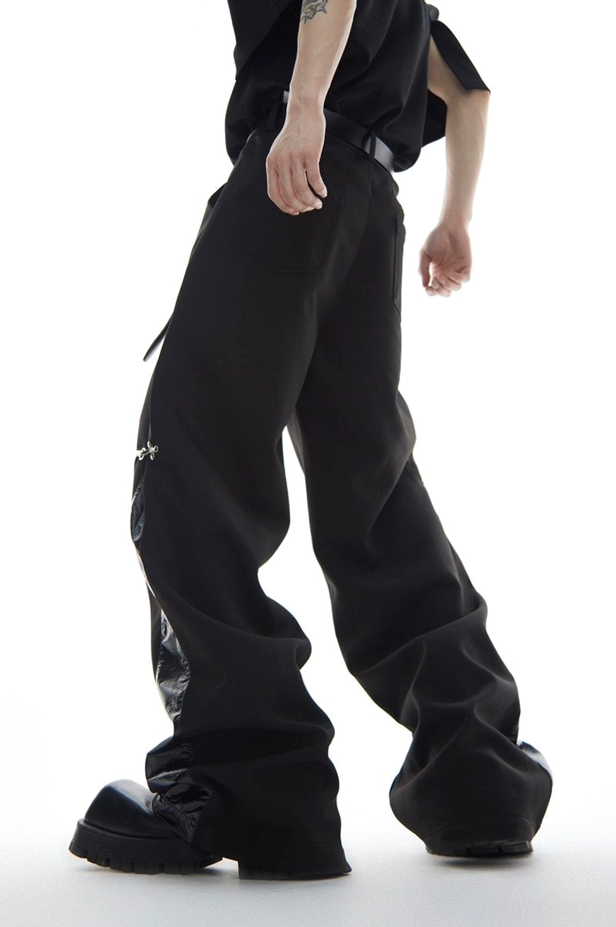 Rear three-quarter view of black wide-leg deconstructed trousers with back pocket glossy side panel and silver hardware