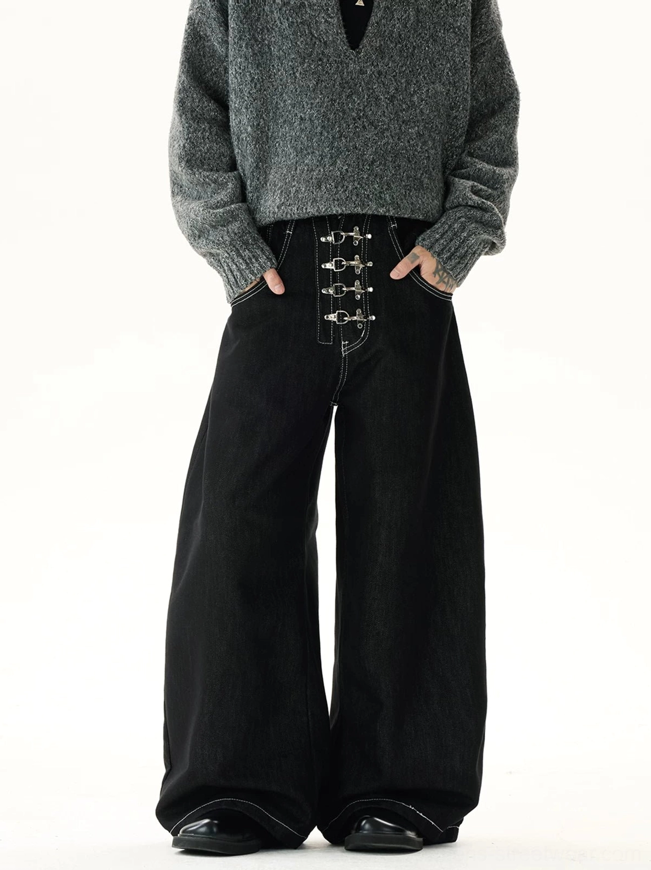 Front view of black wide-leg denim jeans featuring multiple silver hook-and-eye buckle closures, high waist, contrast topstitching, and punk streetwear styling