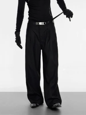 Front view of black high-waisted wide-leg double pleat trousers styled with a silver buckle belt in a minimalist studio