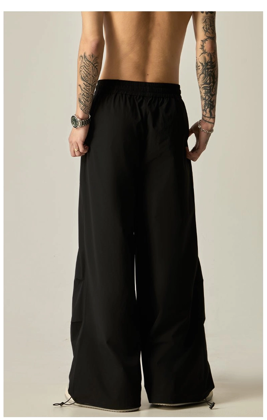Black wide leg drawstring pants for men shown from the back with a clean draped silhouette and adjustable hems