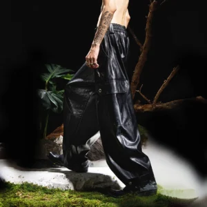 Side walking view of black wide-leg faux leather cargo pants with elastic waistband, loose fit and snap cargo pocket