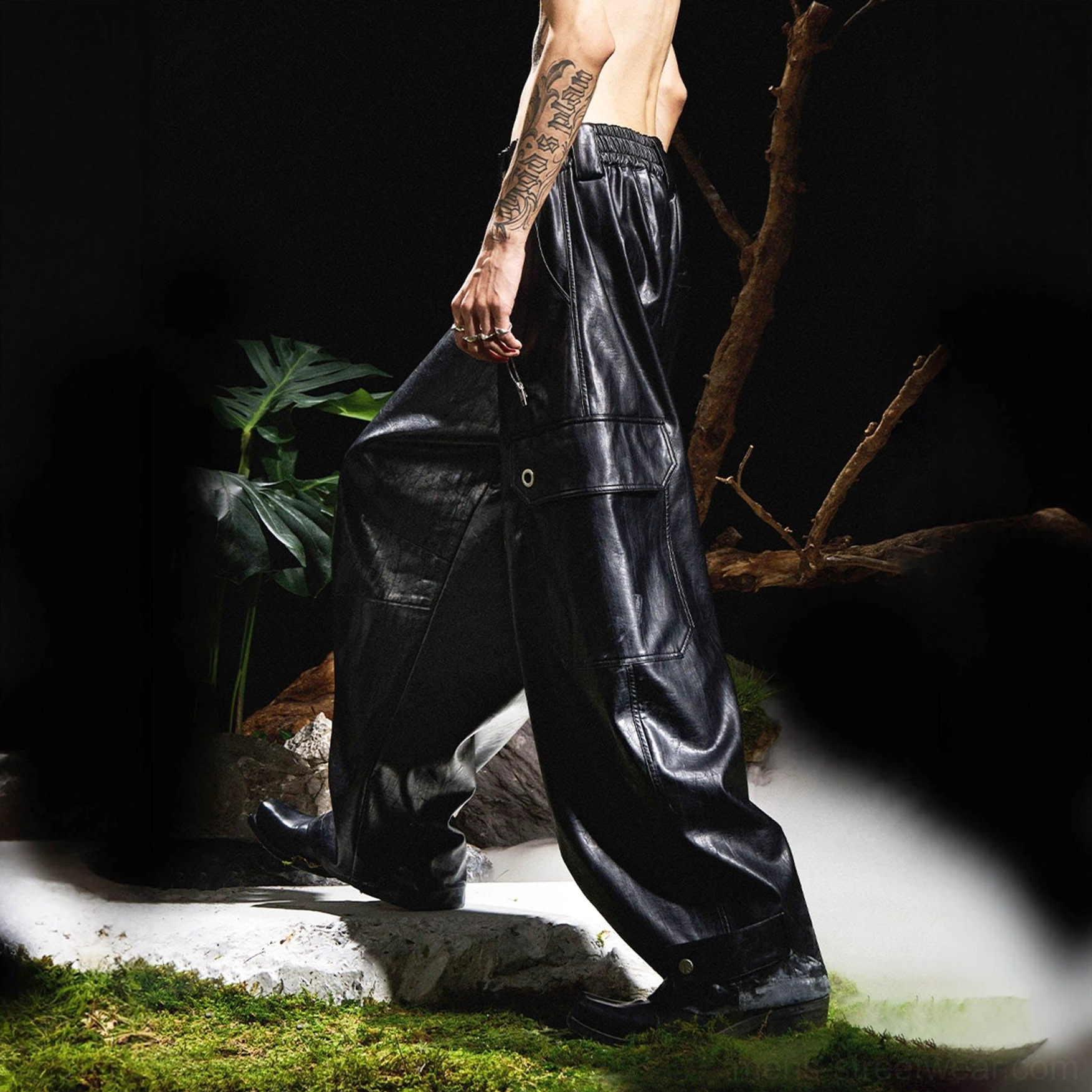 Side walking view of black wide-leg faux leather cargo pants with elastic waistband, loose fit and snap cargo pocket