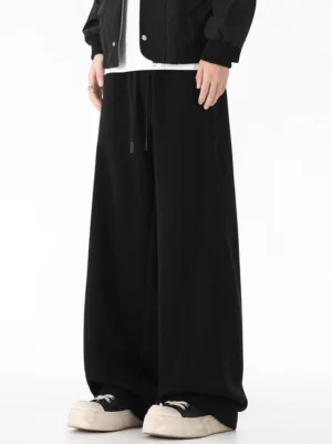 Black wide-leg sweatpants in a full-body front view styled with a matching black bomber jacket, white T-shirt, and relaxed streetwear sneakers