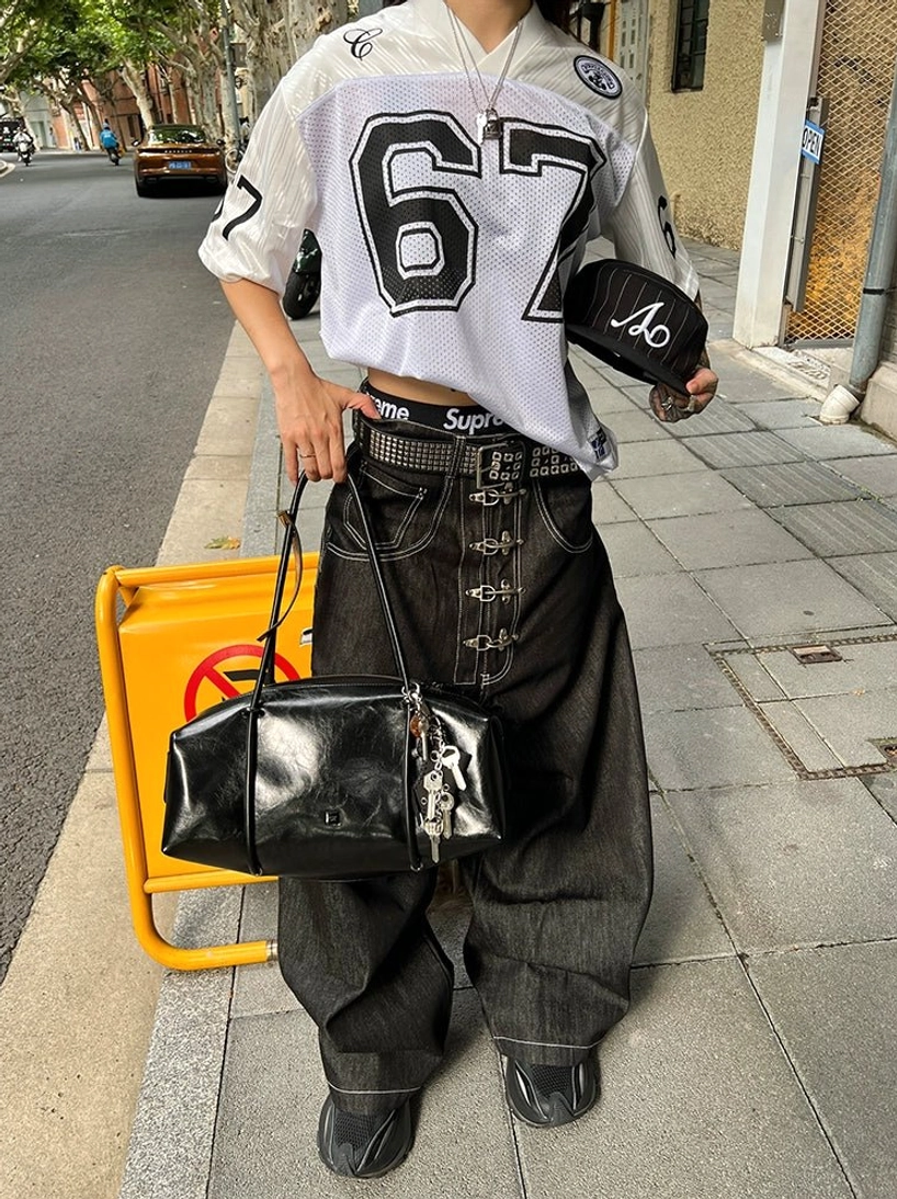 Black wide leg hook closure contrast stitch jeans styled with football jersey on urban city sidewalk