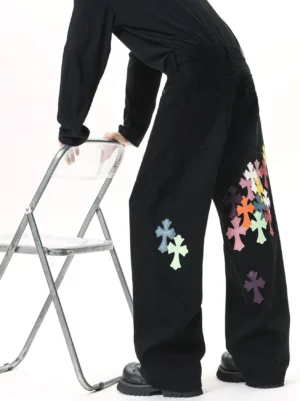 Black wide leg streetwear jeans with colorful cross patches shown from the back three-quarter view with chunky black boots