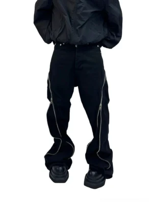 Back low-angle view of black wide-leg denim jeans with exposed silver curved zippers, studded waistband, and black platform loafers