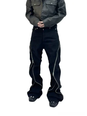 Front view of black wide-leg zipper jeans with curved silver leg zippers, metal studded waistband, and relaxed streetwear fit