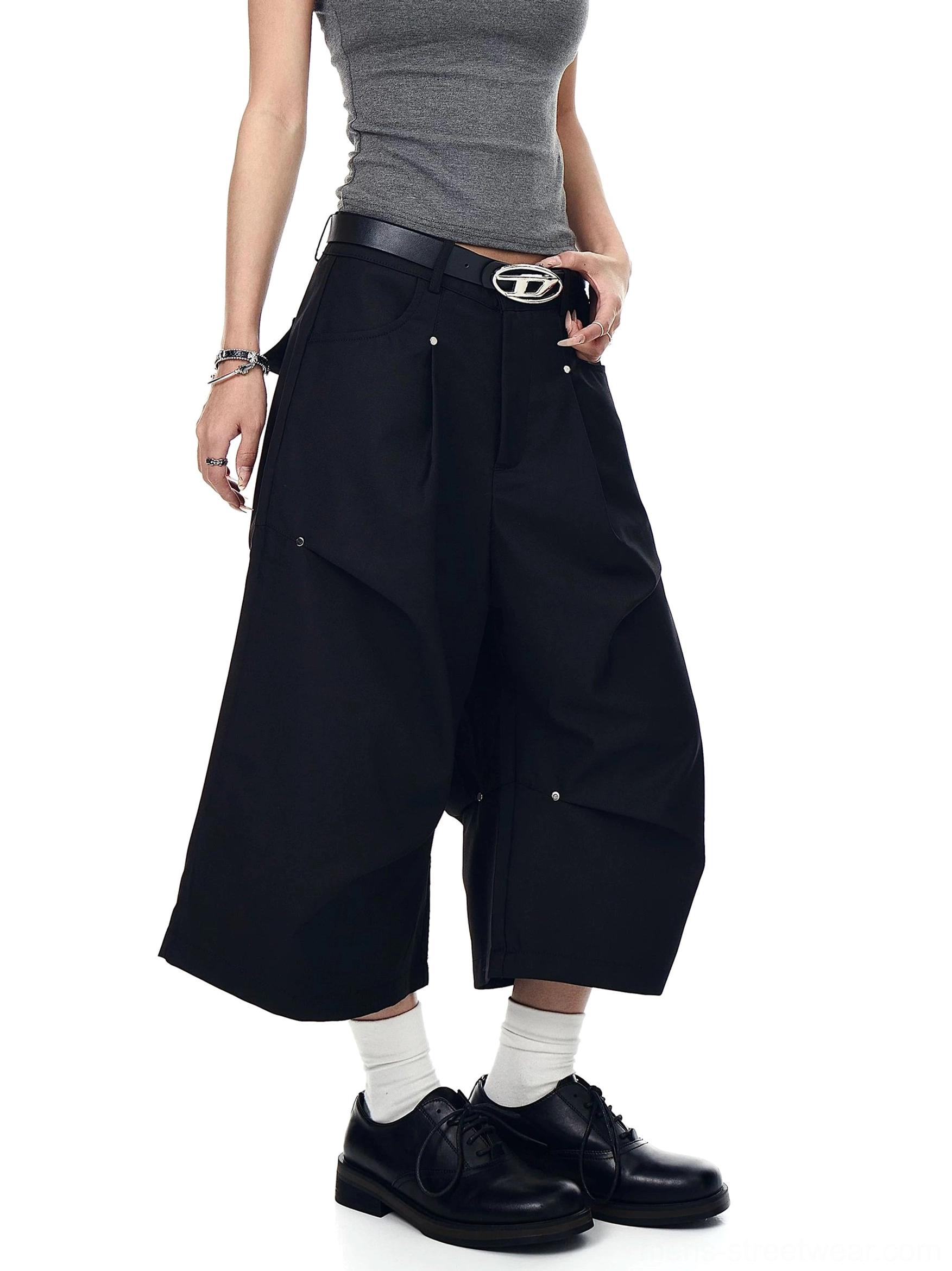 Black wide-leg longline streetwear shorts viewed from the side with stud accents, belt loops, and practical pockets