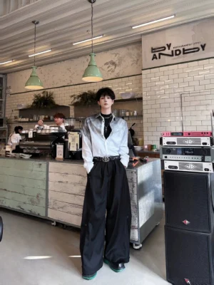Black wide leg pleated trousers styled with a gradient shirt and leather belt in a modern coffee shop setting