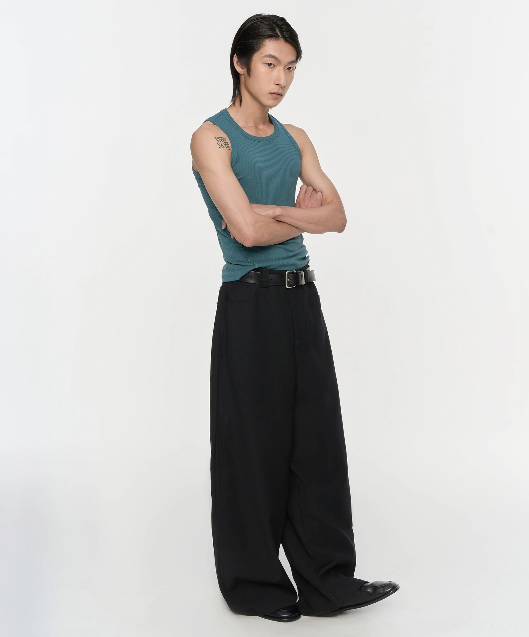 Black wide-leg pleated trousers shown from the side with a streamlined loose leg and contemporary minimalist streetwear styling