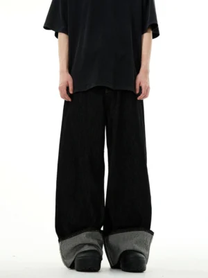 Front full-body view of black extra-long wide-leg denim jeans with contrasting grey reverse rolled cuffs