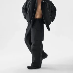 Black wide-leg structured pocket utility cargo pants for men shown in a front three-quarter full-body studio outfit with oversized thigh flap pockets